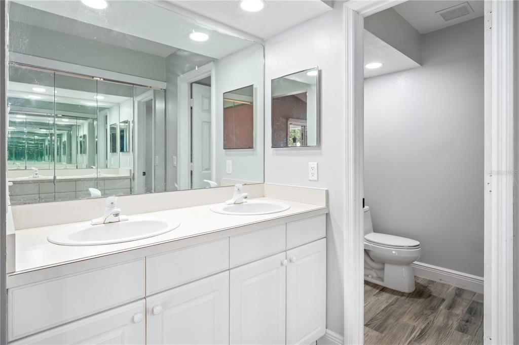 Double sink vanity in the en-suite with ceramic wood-look tile flooring
