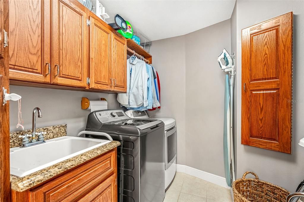 Large indoor laundry room with soaking sink and cabinets