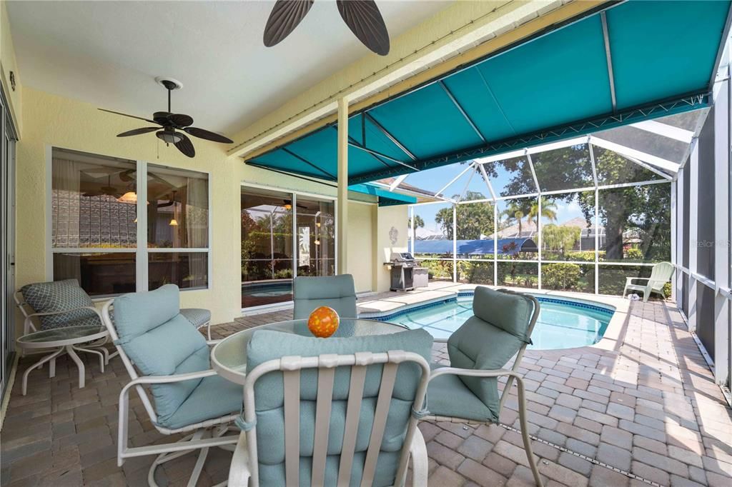 Large covered brick paver lanai with sun shade perfect for hosting and entertaining with multiple entrances granting easy access to inside of home.