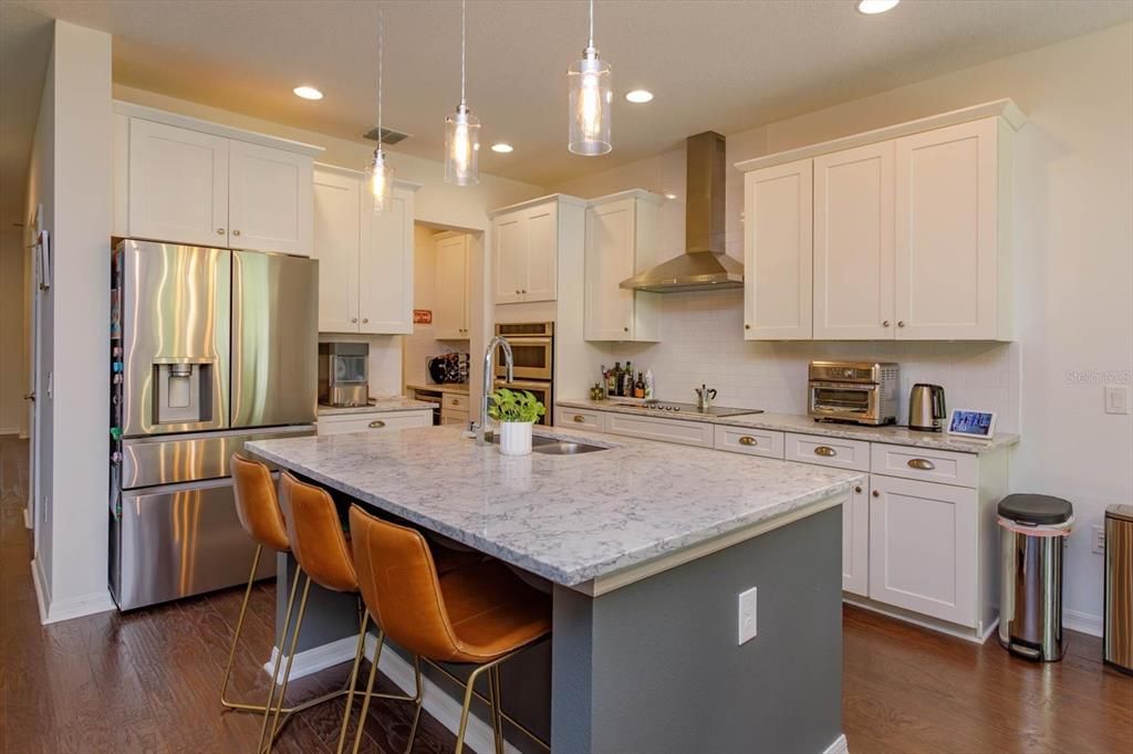 The Heart of the Home!  Expansive island, decorative pendant lighting, Quartz countertops, Subway Tile, 42 inch White cabinetry, Built In Double Oven/Microwave, Sleek Glass Top Range and Stainless Steel venting system.