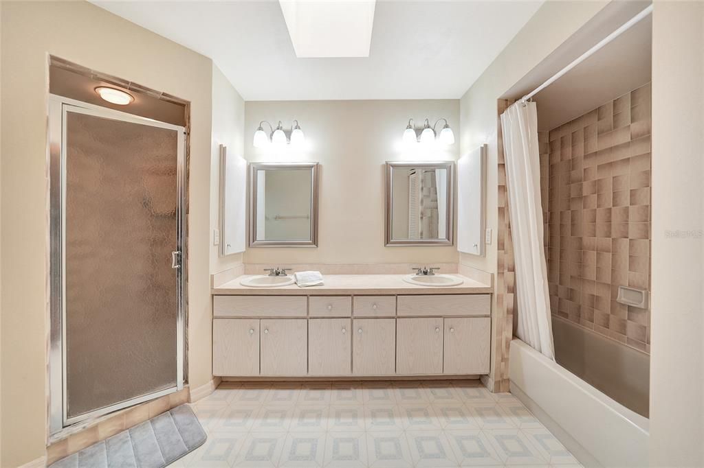 Primary bathroom- tub/shower combo on right and walk in shower on left with dual sinks