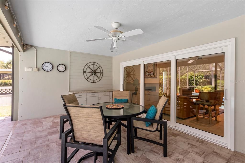 Covered dining Alfresco with access from family room and breakfast room. Notice the cabinet  along the far wall with granite counter. Ideal for serving refreshments or lunch!