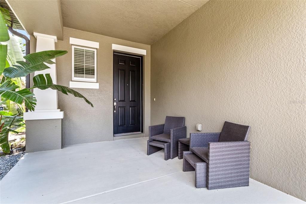Entryway to your new home has a front patio seating area & lush landscaping for privacy & shade.