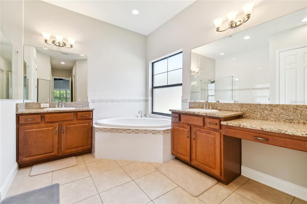 Downstairs Owner's Bathroom with double vanity, Tub, and walk-in shower