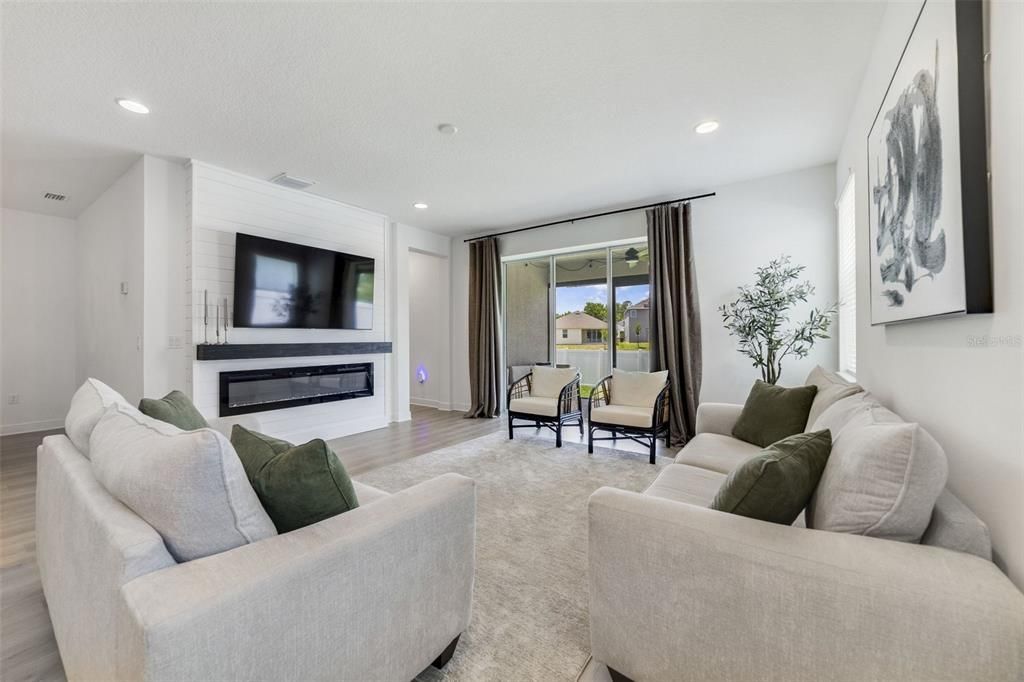 The kitchen overlooks a spacious dining area as well as the central gathering space with a chic FIREPLACE built-in to a feature wall and TRIPLE SLIDING GLASS doors that open up to the screened lanai, perfect for indoor/outdoor living.