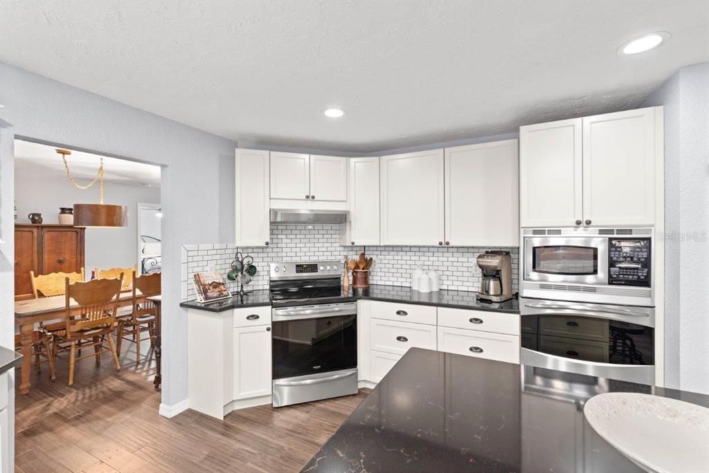 Huge gourmet kitchen with polished granite countertops a island, custom wood cabinetry, stainless steel appliances, and an antique farmhouse-style single-bowl sink with double drainboards pulled directly from a historic home in Bradenton!