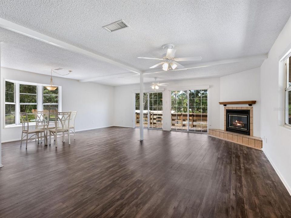 The spacious living/dining room has vinyl plank flooring (installed in 2019), a woodburning fireplace and two sets of sliders onto a large balcony.