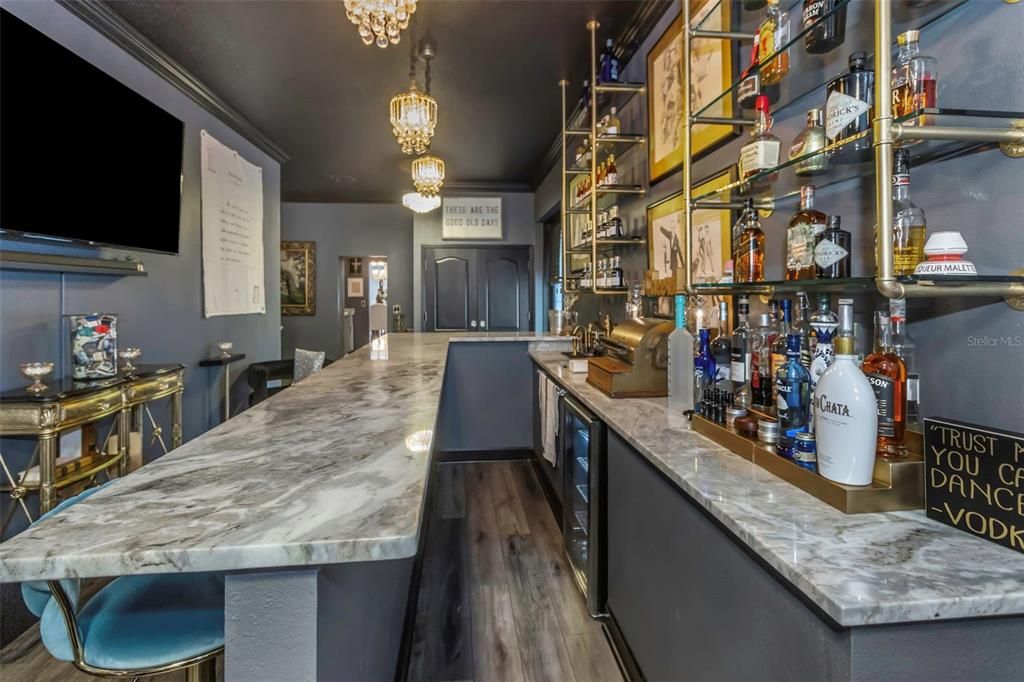 The flooring in the bar is luxury vinyl and waterproof. Notice the built-in refrigerator and whimsical antique cash register that conveys.