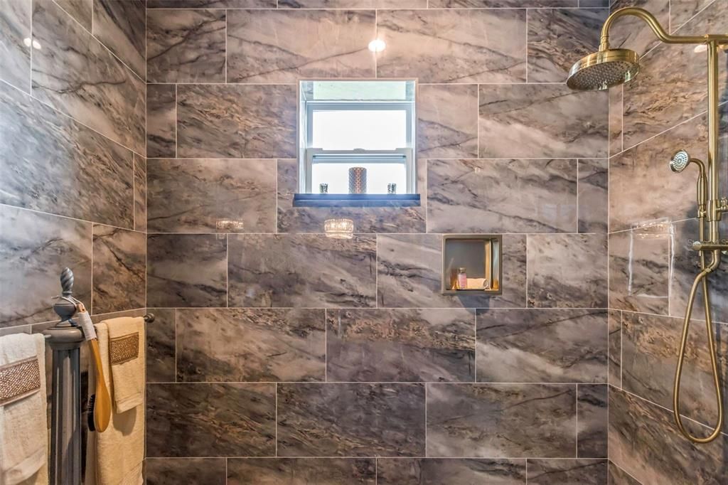 4th bath adjoining the home theater has large Roman Shower with floor to ceiling polished porcelain tile