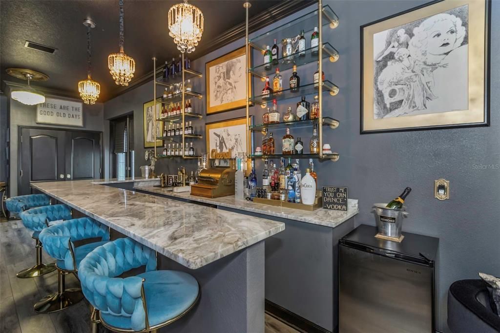 The flooring in the bar is luxury vinyl and waterproof. Notice the built-in refrigerator and whimsical antique cash register that conveys.