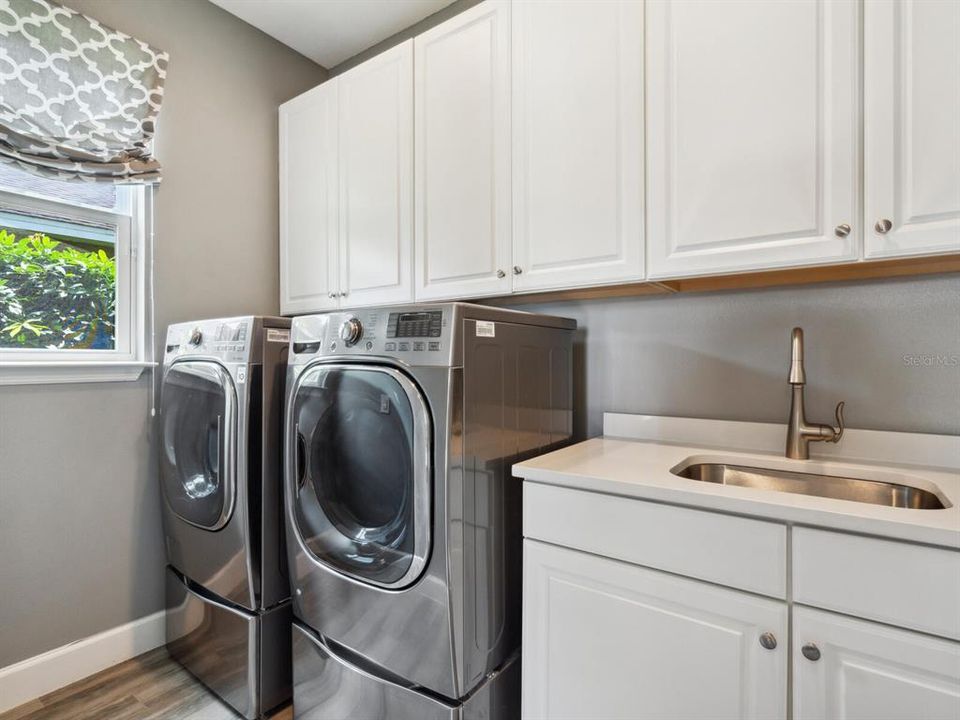 Spacious laundry room with extra storage, utility sink and full-size washer and dryer.