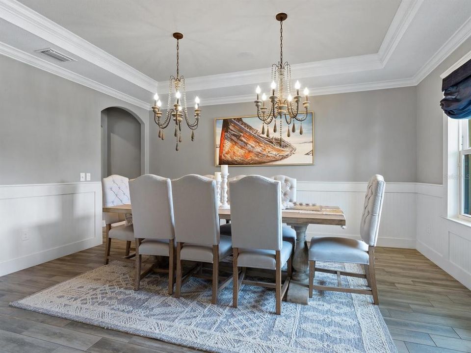Elegant dining room with beadboard walls and tray ceilings.