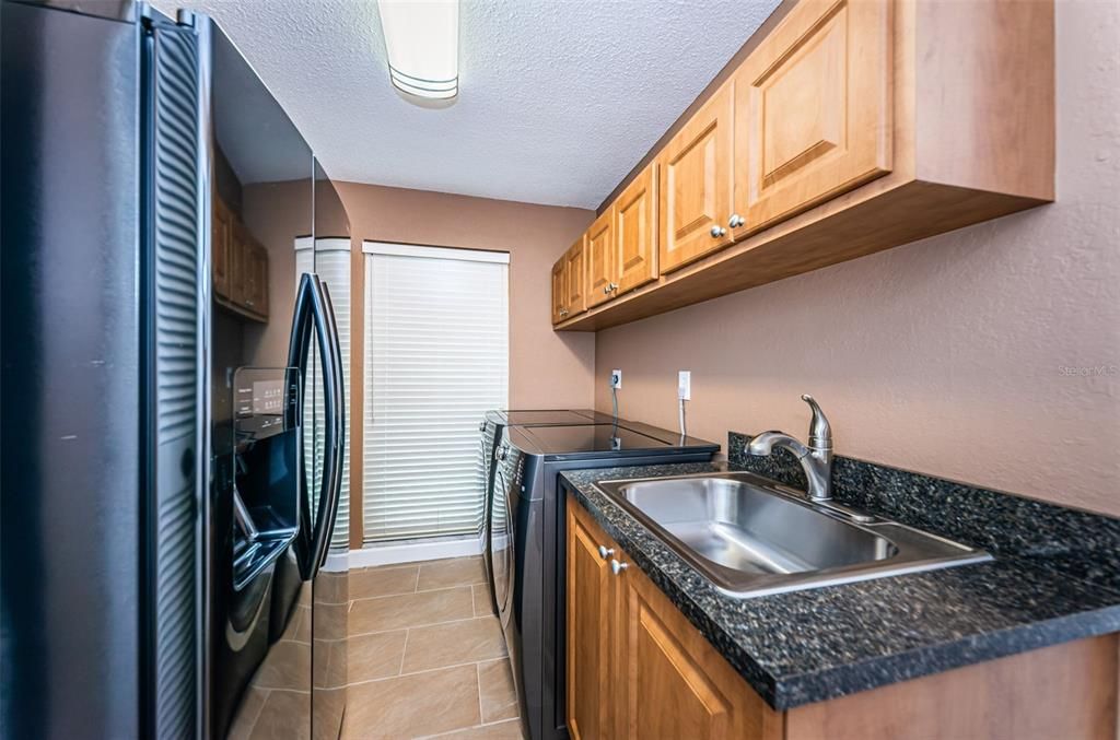 Spacious laundry room with lots of storage.  Washer, Dryer and Extra Fridge convey.