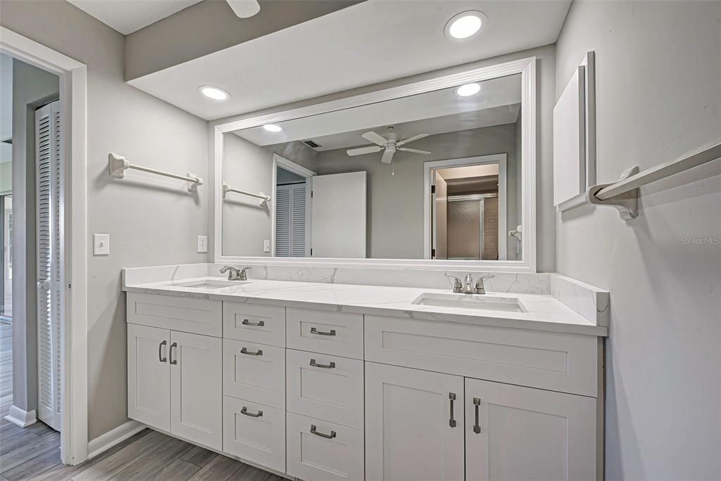 Professionally updated primary bathroom with quartz countertops, plenty of storage and new lighting.