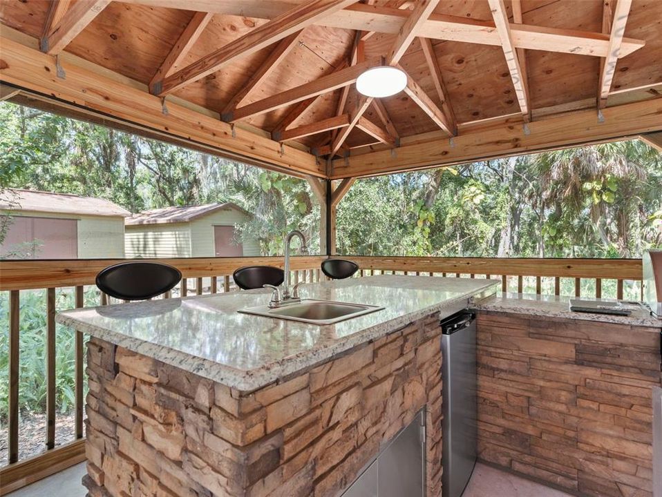 Impressive outdoor kitchen offers ample seating at bar AND table  / seating areas
