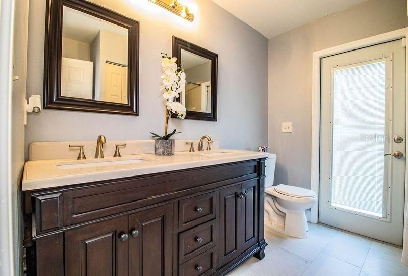 This full bathroom has a shower and a door leading to a pool area.