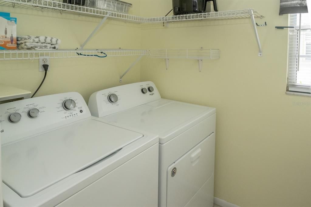Laundry Room, right off the kitchen, features newer washer and dryer, ceramic tile flooring, and plenty of shelving.