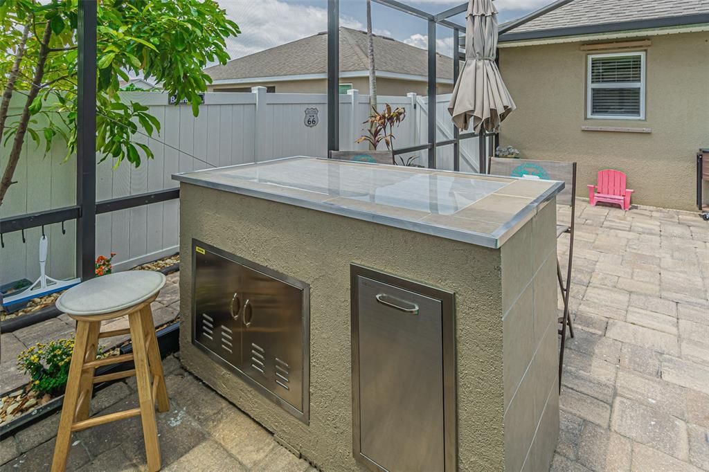 Additional workspace in grilling area with stainless trash pull out and additional stainless cabinet.
