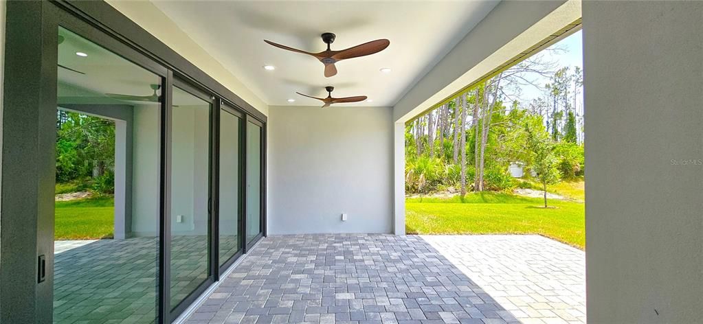 Rear paved and covered porch includes 8 can lighting fixtures and three ceiling modern fans