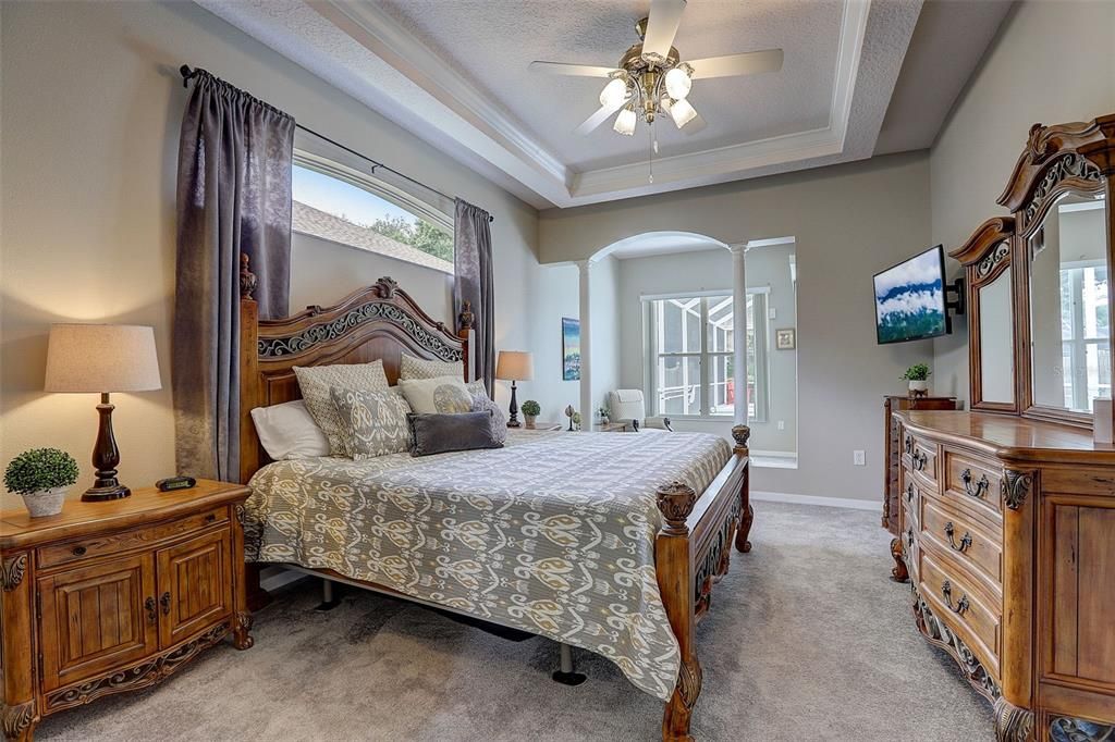 Large Primary Suite features high tray ceilings, natural light, a reading nook with sliders to the lanai, two walk in closets, and fully remodeled bathroom!