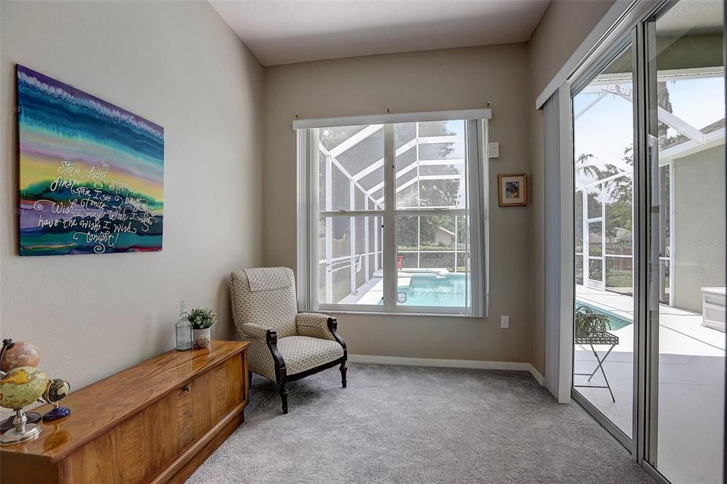 Large Primary Suite features high tray ceilings, natural light, a reading nook with sliders to the lanai, two walk in closets, and fully remodeled bathroom!