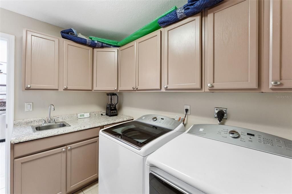spacious laundry room, you'll appreciate the abundance of storage provided by numerous cabinets and a sink.