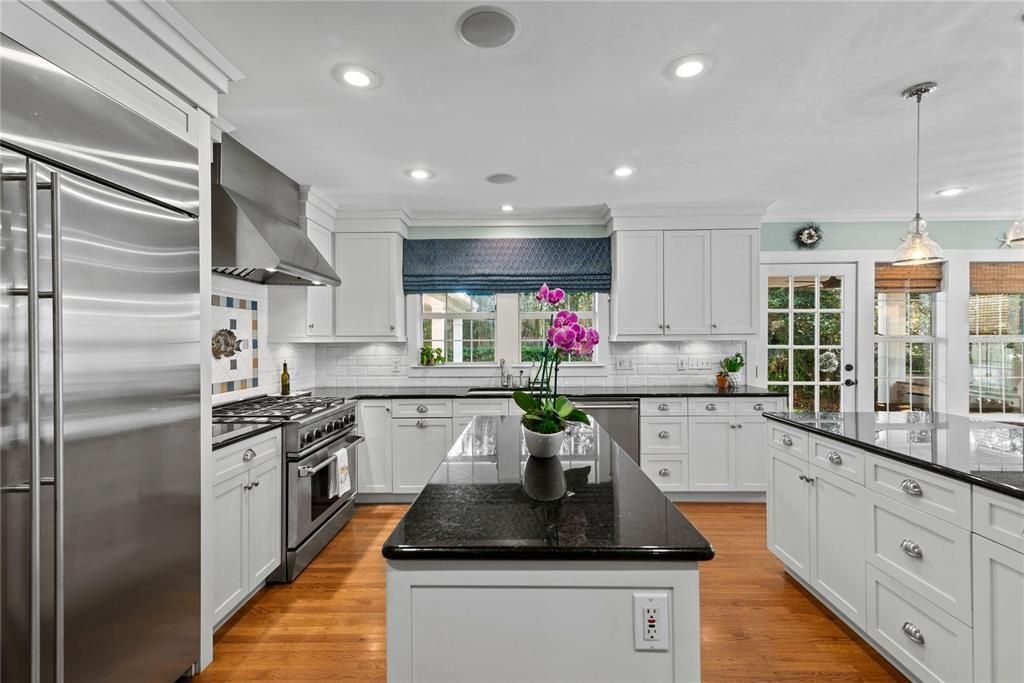 Beautiful kitchen with 6 burner gas range, range hood, bar seating with pendant lighting, solid wood cabinetry and granite counters.