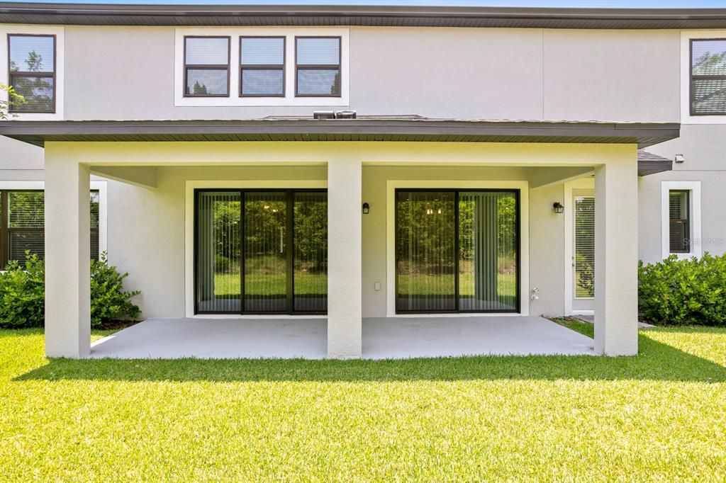 Backyard lanai with two sets of sliding glass doors, can be screened in or extended out as a cage for patio and pool.