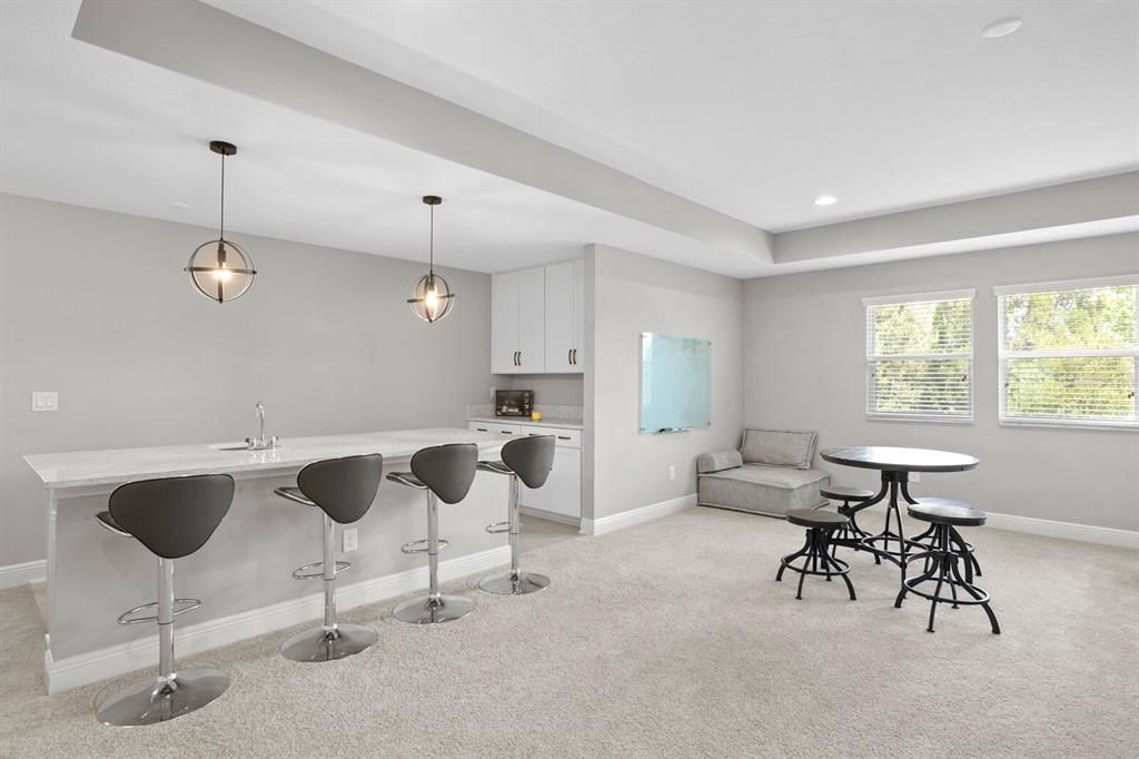 Seating area at the wet bar with sink, mini fridge, and cabinetry.