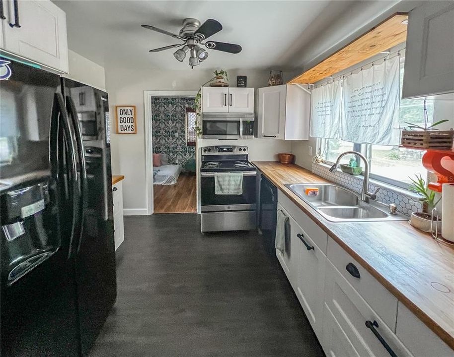 The Kitchen features modern cabinetry and butcher block countertops. The door to the 4th Bedroom with the en-suite Half Bath is seen near the center of this photo.