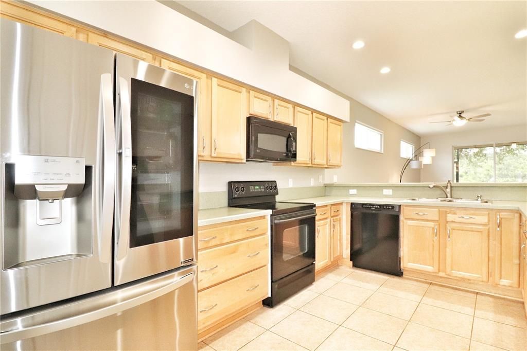 The spacious kitchen features maple cabinets, a smoothtop range, a 2020 InstaView refrigerator, a 2020 garbage disposal, and a closet pantry