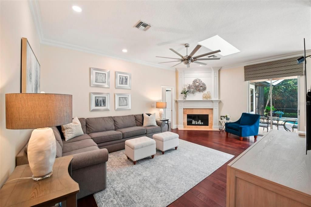 Family room with wood burning fireplace, skylight and pool view