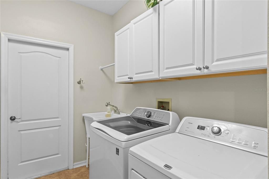 The laundry room is located off the garage and features custom storage shelving for cleaning supplies.