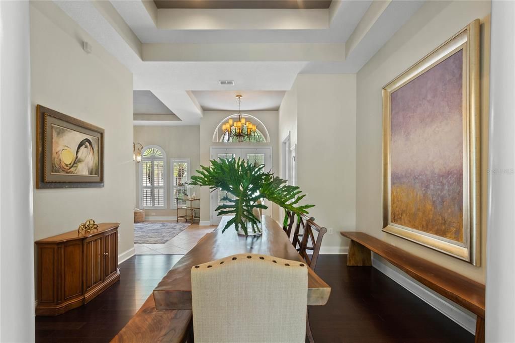 The formal dining room features a tray ceiling, wood look flooring and access to the pool area. The table and large art display are negotiable.