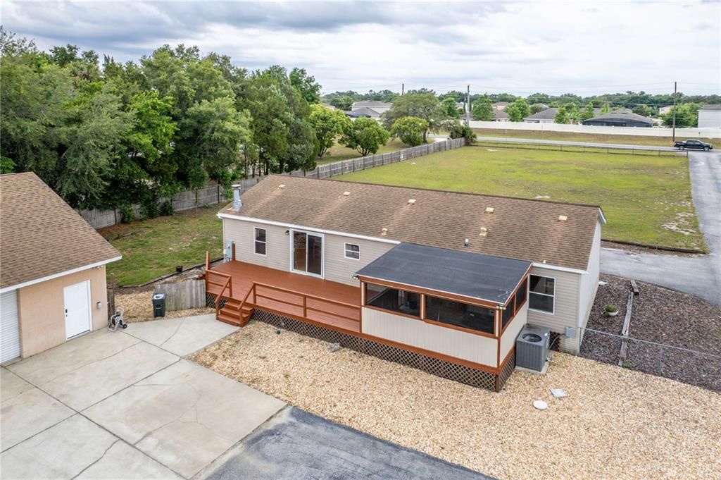 A large back deck and screened lanai are located on the rear of the home. A fenced play area is to the left in this photo.