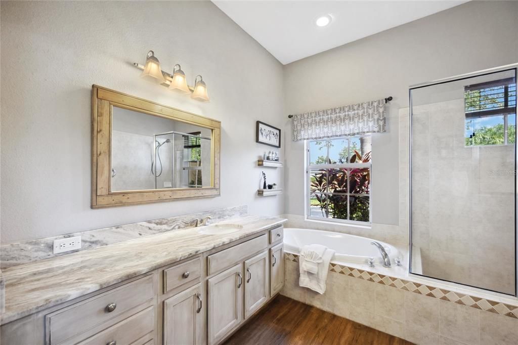 Ensuite bathroom with oversized quartz countertops, a large soaking garden tub and walk in Roman shower.
