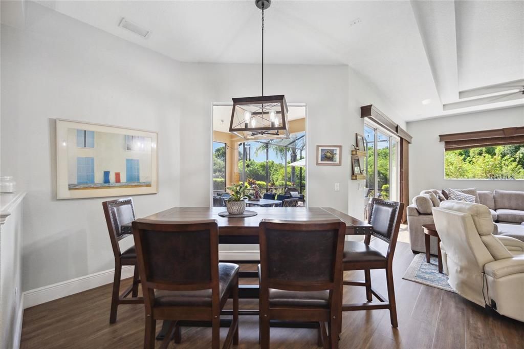 Dining room nestled perfectly looking out into pool area and right next to family room and kitchen. High end light fixtures add style and formality.