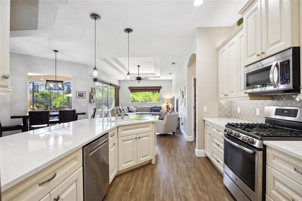 Modern designed kitchen overlooks family room. Quartz counter top, modern tile backsplash, and stainless steel appliances, gas stove