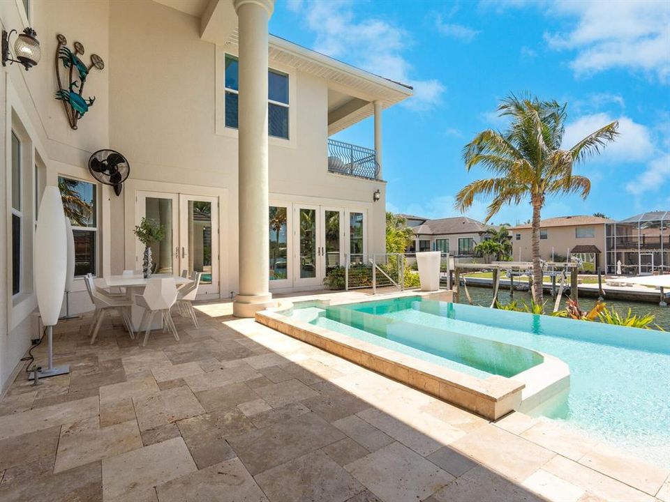 Infinity Pool and travertine deck off of living area and kitchen/dining