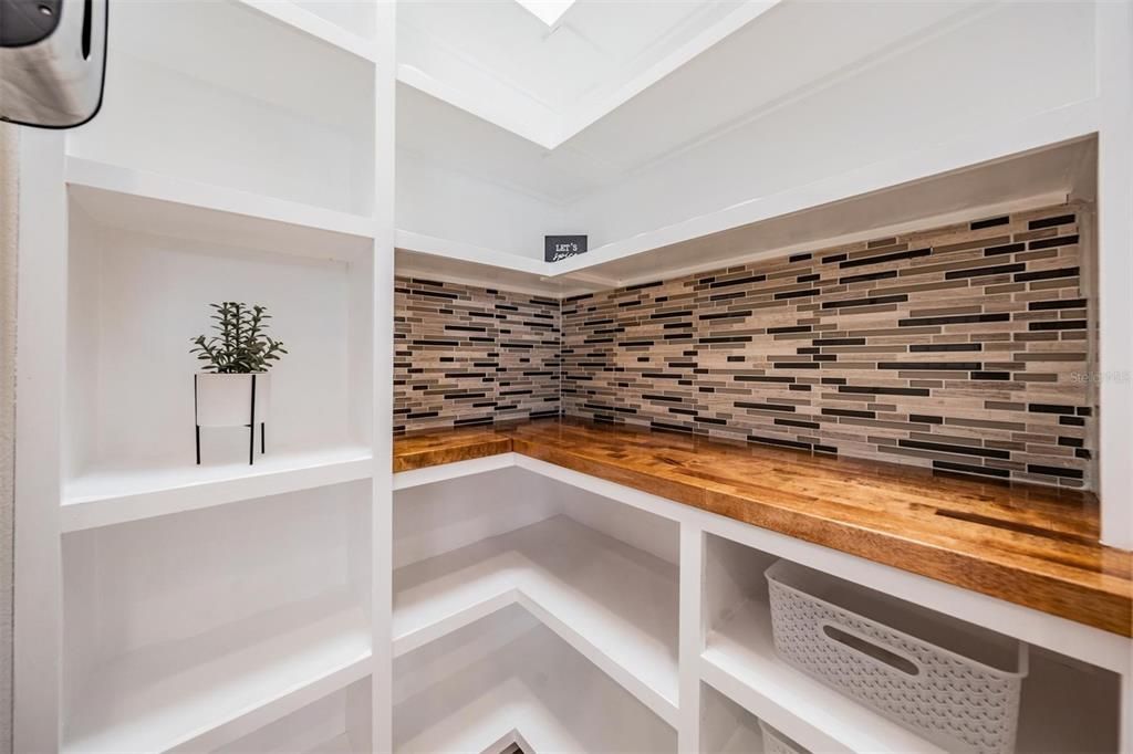 Custom built-in shelving in walk in pantry with electrical outlets