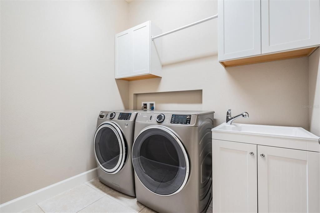 First floor laundry with cabinets, sink and hanging rod