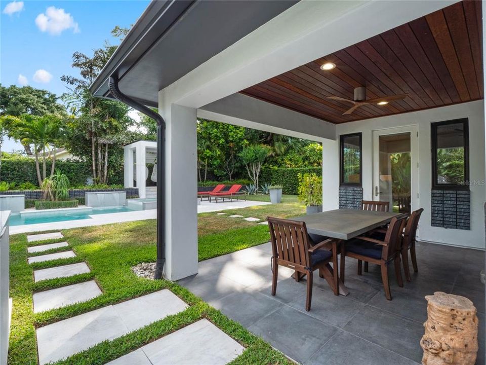 Covered patio with tongue ceiling and stepping stone to the pool