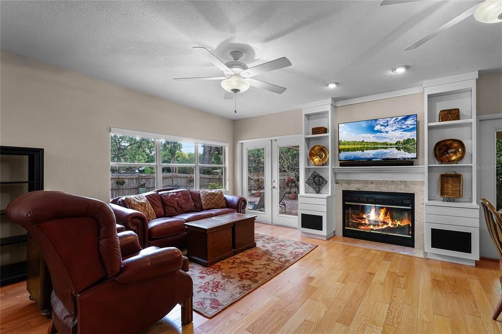 Family room with fireplace and French doors leading to the beautiful backyard