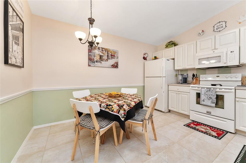 EAT IN KITCHEN HAS TABLE & CHAIRS, CHANDELIER AND WHITE CABINETS.