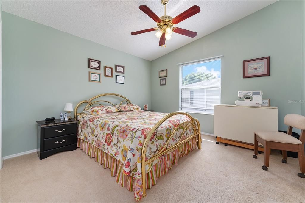 GUEST ROOM WITH LIGHTED CEILING FAN AND WINDOW FOR NATURAL LIGHT (SEWING MACHINE, LINENS,  ITEMS ON WALL AND CHAIR BELONG TO CURRENT RENTER)