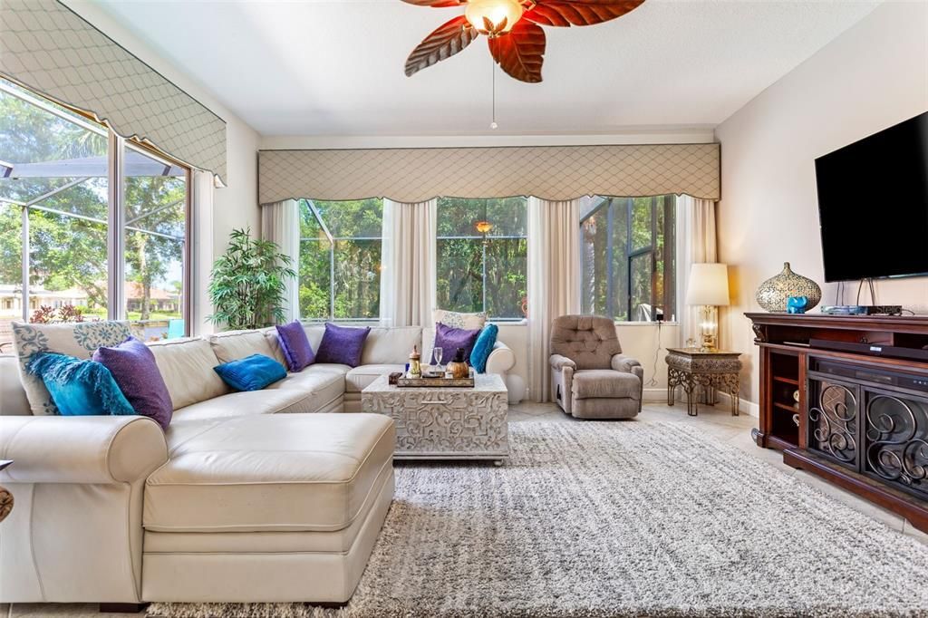 Living room and kitchen with an abundance of windows overlooking cory lake, conservation, and pool