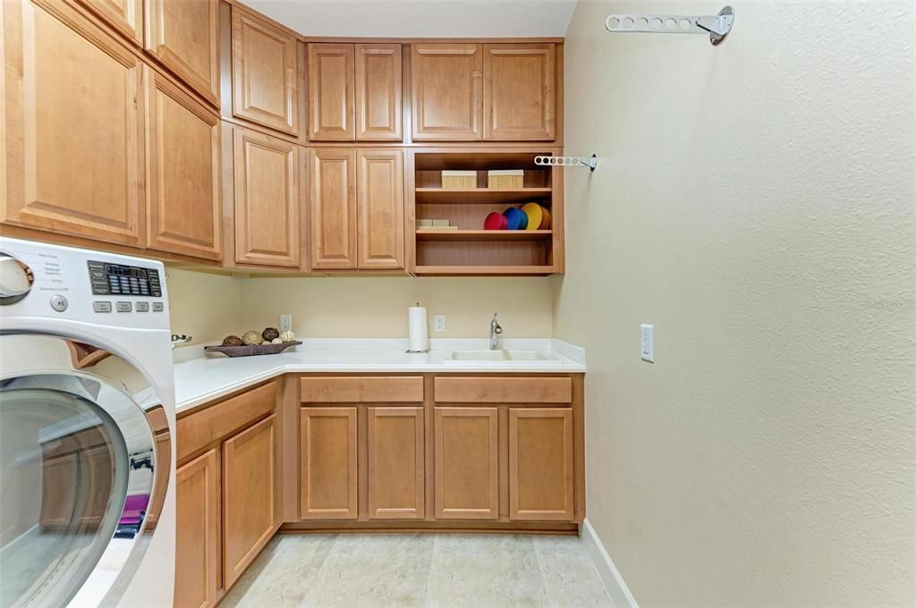 Separate laundry room with loads of cabinets and utility sink