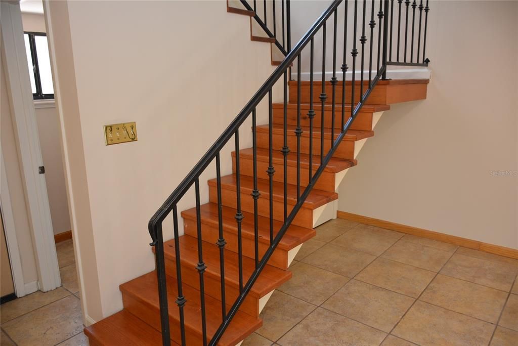 Semi-open Pine staircase with abundant natural light, wrought iron rail, leads to three spacious bedrooms