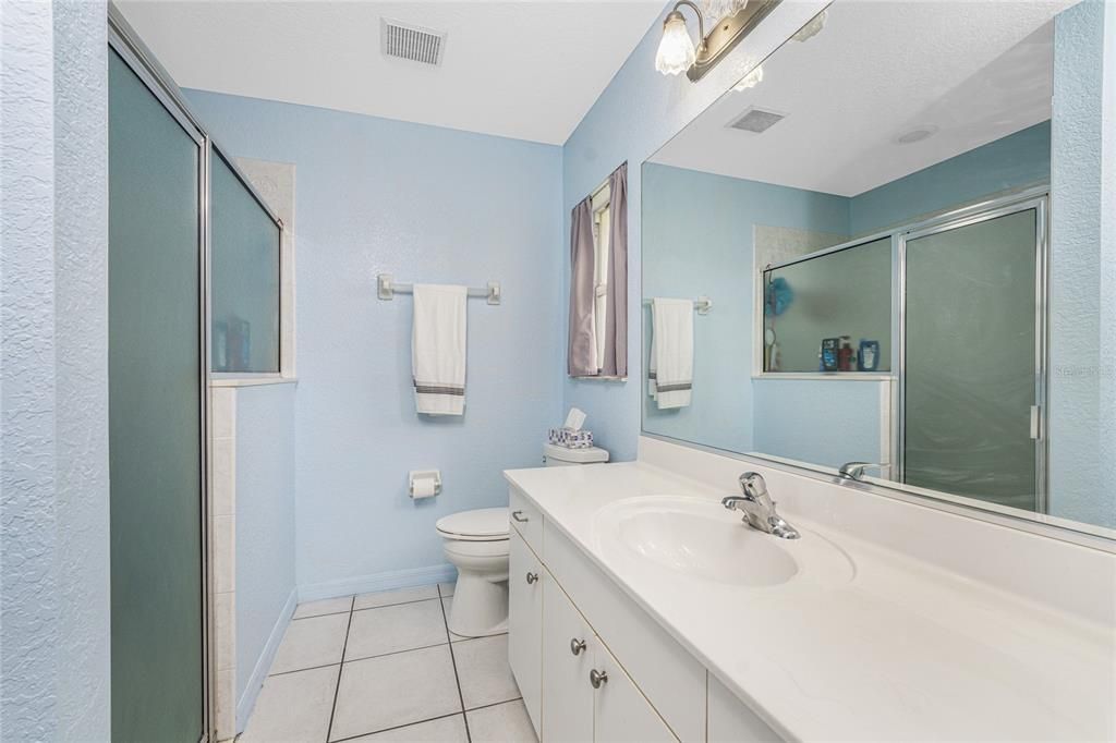 Main bathroom has a step in shower with glass door.