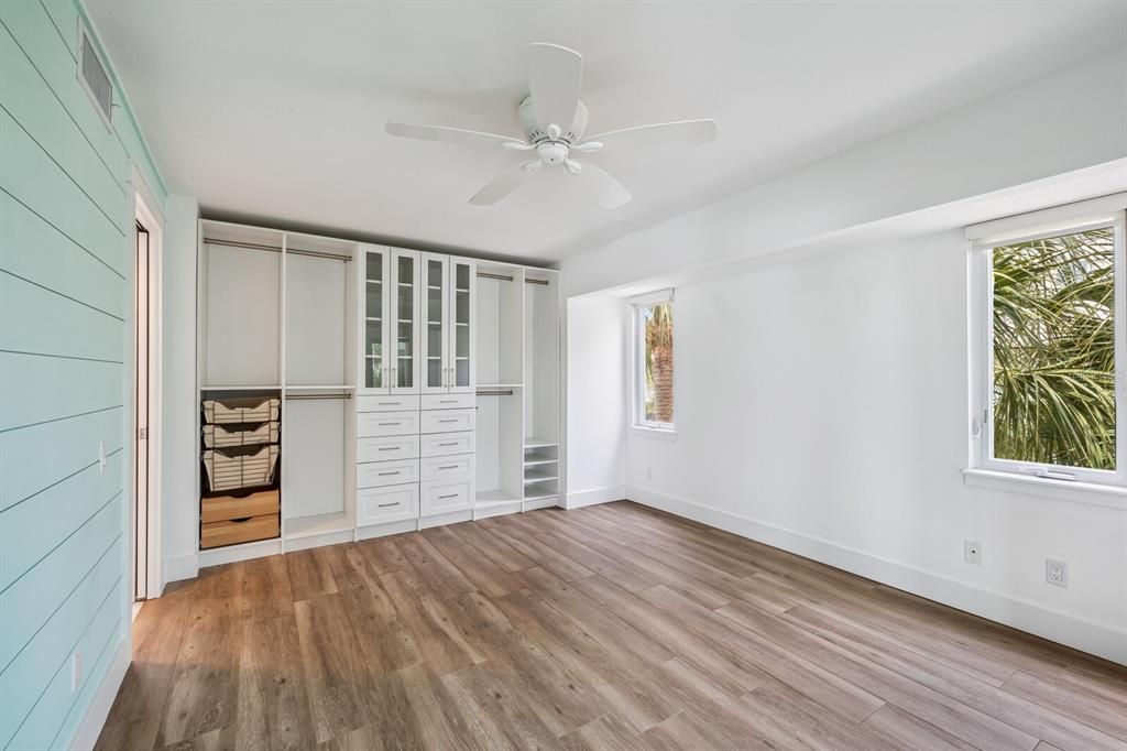 Primary bedroom with custom built-in closet, beachy shiplap wall painted turquoise.